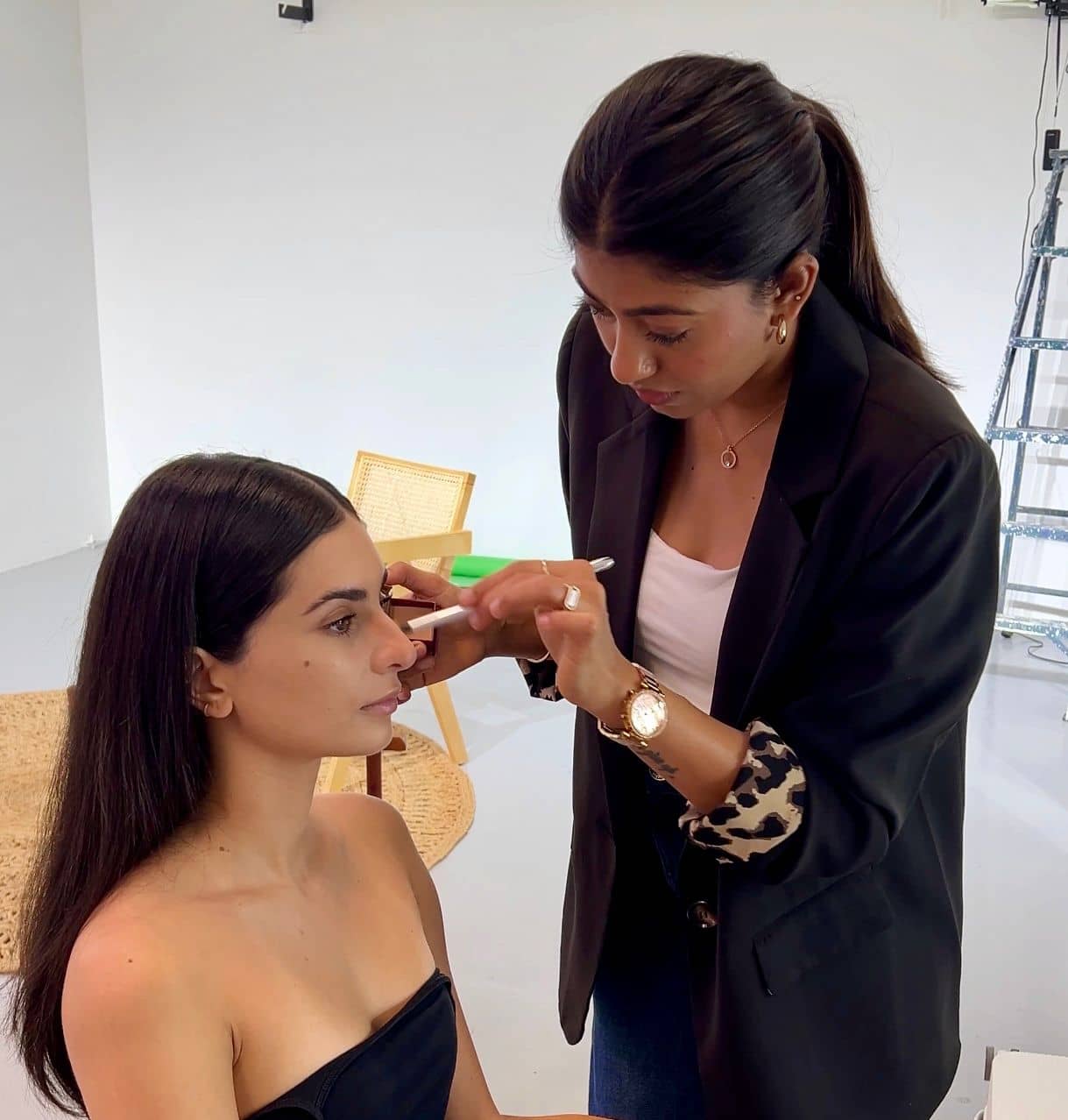 Sheetal Mukhida applying makeup on set, working close to camera under studio lights