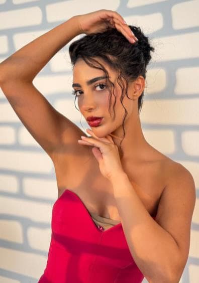 فستان أحمر وجدار من الطوب. مكياج وشعر من شيتال موكهيدا